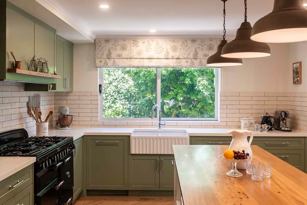 Hartley House French Country Kitchen French-country kitchen at Hartley House with green cabinetry, fluted butler sink, traditional cabinet handles and timber island bench.